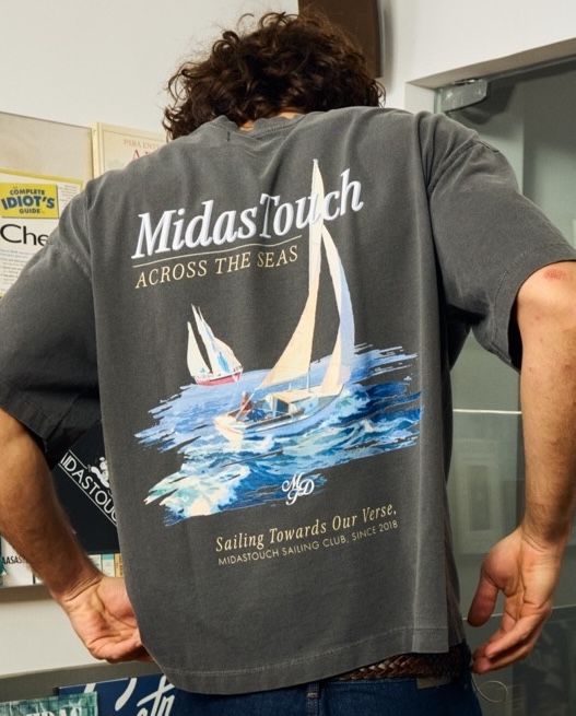 Camiseta cinza com estampa nas costas “MidasTouch Across the Seas” e ilustração de veleiros