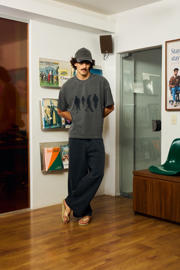 Camiseta cinza estampada com silhuetas de pessoas caminhando, usada com calça jeans larga