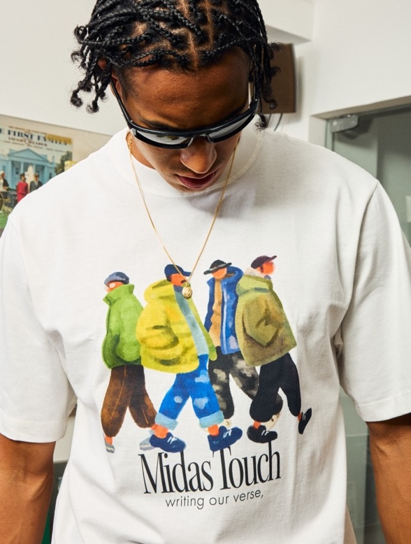 Camiseta branca com estampa “Midas Touch, writing our verse”, usada por modelo com óculos escuros